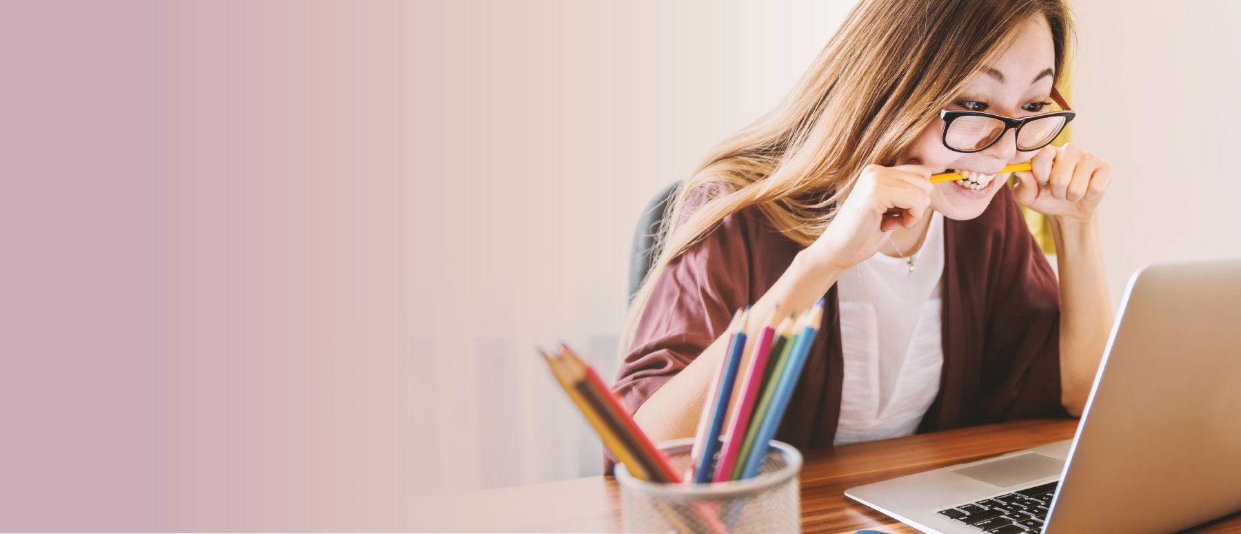 Photograph of woman nervously biting her pencil looking at her computer