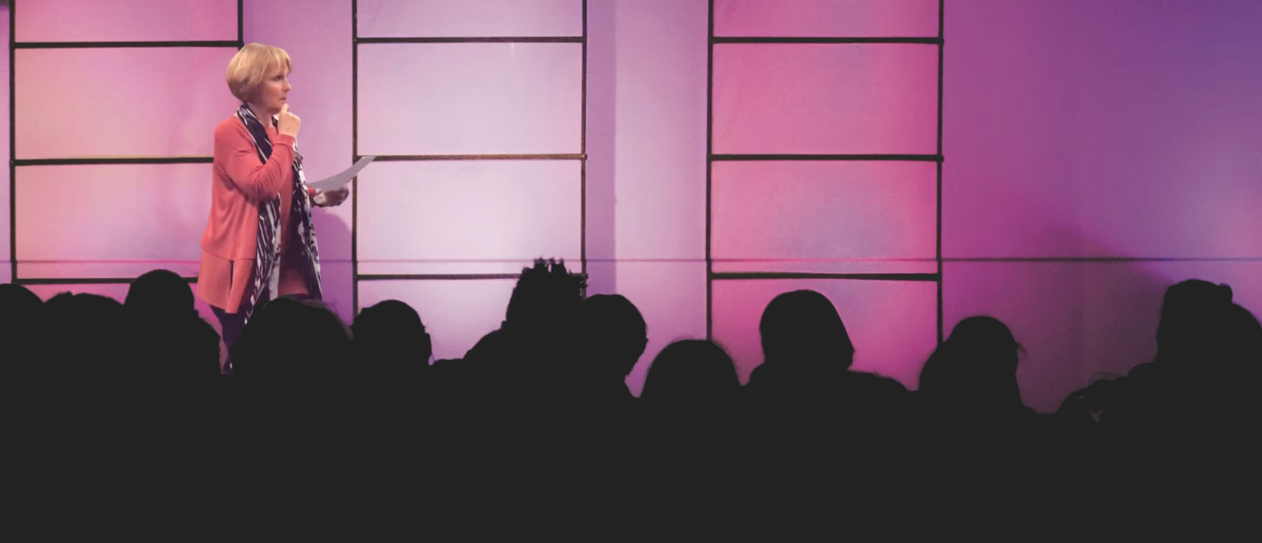 Woman standing on stage reading to audience